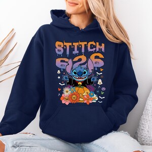May include: Navy blue hoodie featuring a graphic of Stitch from Lilo & Stitch dressed as a vampire, with the text "Stitch 626". The design includes a pumpkin, flowers, and Halloween-themed elements.