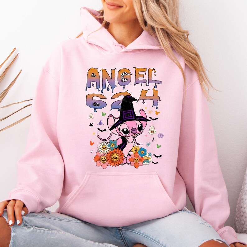 May include: Pink hoodie featuring a graphic of a pink alien wearing a witch hat, surrounded by flowers and Halloween-themed decorations. The text "ANGEL 624" is above the character in a dripping font.