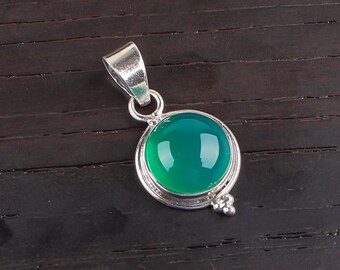 May include: A round, green gemstone pendant with a silver-colored metal setting. The pendant has a polished, glossy finish and a small loop at the top for a chain. The gemstone is a vibrant shade of green.