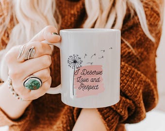 May include: White ceramic mug with a black dandelion design and the text "I Deserve Love and Respect" on a pink background.