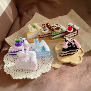 May include: A collection of handmade felt cake slices in various colors and designs, including purple, blue, pink, yellow, green, and brown. The cakes are decorated with frosting, sprinkles, and other embellishments.
