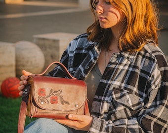 Etno-Elegant ist eine handgefertigte Ledertasche mit Holzeinsätzen, Stickereien, Blumen und einem codierten Amulett aus Epoxidharz.