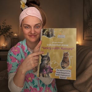 May include: A spiral-bound coloring book titled Unity with Nature, featuring cat illustrations on a yellow cover. The text reads Stress-Relief COLOURING BOOK, Unity with Nature, for veeeeery tired Adults, and For Harmonizing Inner Negativity. With Therapeutic Action!