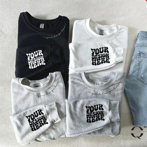 May include: Four sweatshirts in black, white, and two shades of gray, folded and arranged on a white surface. Each sweatshirt has the text "YOUR DESIGN HERE" printed on the front in a retro font.