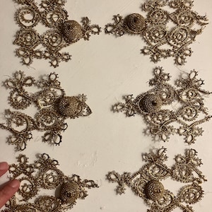 Może przedstawiać: Sześć złotych koronkowanych serwetek z wypukłym środkiem, każda z unikalnym wzorem. Serwetki są ułożone w dwóch rzędach po trzy na białym tle.