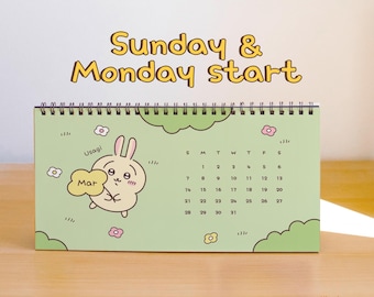 May include: A spiral-bound desk calendar with a light green background featuring a cartoon rabbit holding a sign that says Mar. The text Sunday & Monday start appears above the calendar grid, which displays the days of the month.