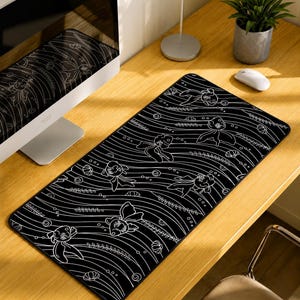 May include: A rectangular desk mat featuring a black background with a white line-art pattern of goldfish, aquatic plants, and bubbles. The design consists of flowing horizontal wavy lines that create a sense of movement across the surface.