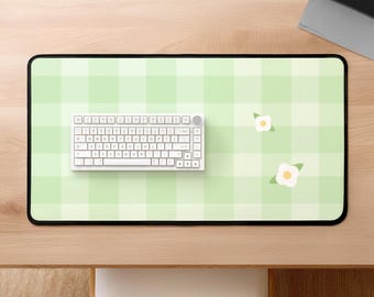 Pode incluir: Um tapete de mesa xadrez verde e branco com um teclado branco e duas flores brancas com caules verdes.