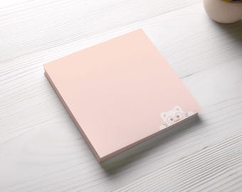 May include: A stack of pink sticky notes with a white cat peeking out from the bottom edge.