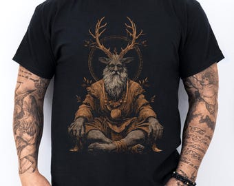 May include: Black t-shirt with a detailed illustration of a seated figure with deer antlers, a long white beard, and a golden halo. The figure wears a brown robe and jewellery. The design is centered on the shirt.