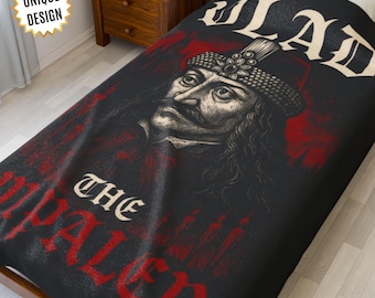 May include: A black blanket featuring a detailed illustration of Vlad the Impaler, with the text "Vlad the Impaler" in white and red. The blanket has a unique design and is made for a dark aesthetic.