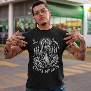 Santa Muerte Gothic Shirt - Holy Death T-Shirt featuring Day of the Dead skull design. Perfect Mexican folk art skeleton top for Dia de los Muertos celebrations or as a unique gift idea. Stylish and symbolic gothic tee for fans of Santa Muerte.