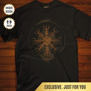 May include: Black t-shirt featuring a brown, stylized Viking symbol within a circular design. The shirt has the text "EXCLUSIVE. JUST FOR YOU" at the bottom. The shirt is labeled "UNIQUE DESIGN" and "UNISEX".