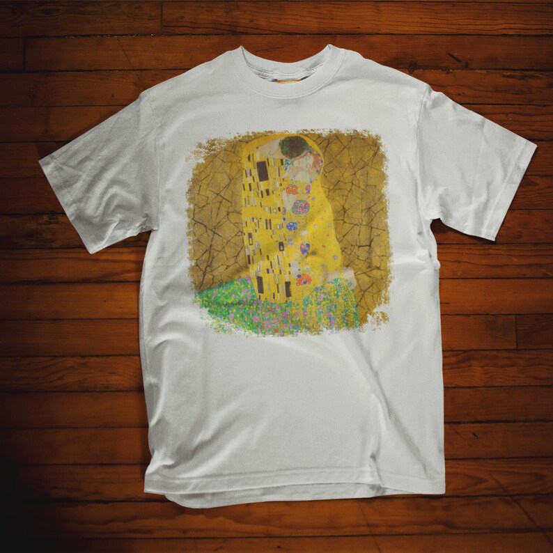 Distressed style t-shirt featuring Gustav Klimt painting The Kiss, rendered in faded gold and black tones on soft, white cotton fabric, suitable for art lovers.