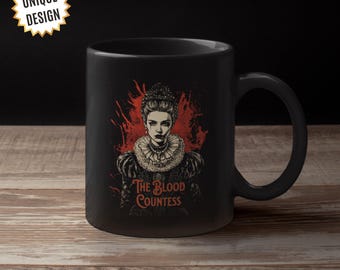 May include: Black ceramic mug featuring a white image of a woman wearing a crown with the text "The Blood Countess".