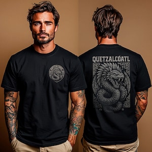 以下が含まれることがあります： 黒いTシャツ。背中には「QUETZALCOATL」の文字と、蛇の精巧なイラストが描かれています。前面には、同じ蛇を使った小さな円形デザインがあります。デザインはグレーの色合いです。