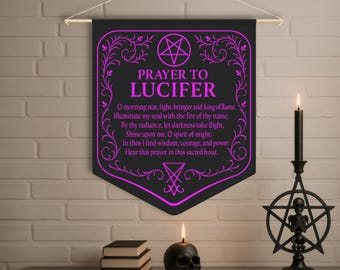 May include: Black banner with the text "PRAYER TO LUCIFER" in purple, along with a prayer. The banner is hanging above a table with a skull candle, books, and a black candle holder with a skeleton inside a pentagram.
