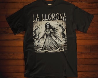 Könnte beinhalten: Schwarzes T-Shirt mit einem weißen Grafikdruck einer Frau in einem weißen Kleid mit einem gespenstischen Gesicht. Der Text "LA LLORONA" ist über dem Grafikdruck gedruckt.