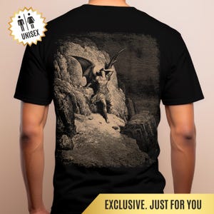 May include: Black unisex t-shirt with a sepia-toned illustration of a winged figure on a rocky landscape. The graphic is in a detailed, classical art style. The shirt has a round neckline and short sleeves. The text "EXCLUSIVE. JUST FOR YOU" is at the bottom.