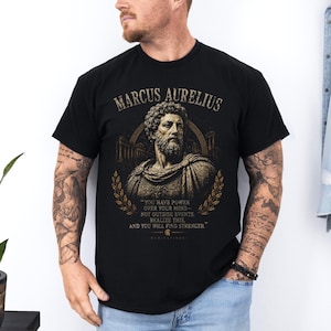 Marcus Aurelius shirt featuring a vintage-inspired portrait of the Roman emperor and famous Stoic philosopher. This stoicism tee is perfect for philosophy lovers, history enthusiasts, self-discipline seekers, and fans of ancient Rome. Motivational philosophy shirt inspired by Stoic wisdom, resilience, virtue, personal growth, and the teachings of Marcus Aurelius.