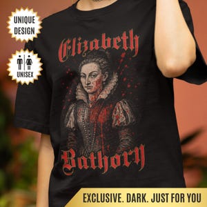 Op de afbeelding: Zwart T-shirt met een rode afbeelding van Elizabeth Bathory, een historische figuur die bekend staat om haar misdaden. De afbeelding toont een portret van Elizabeth met bloedspatten en de tekst "Elizabeth Bathory" en "Bathory" in rood.