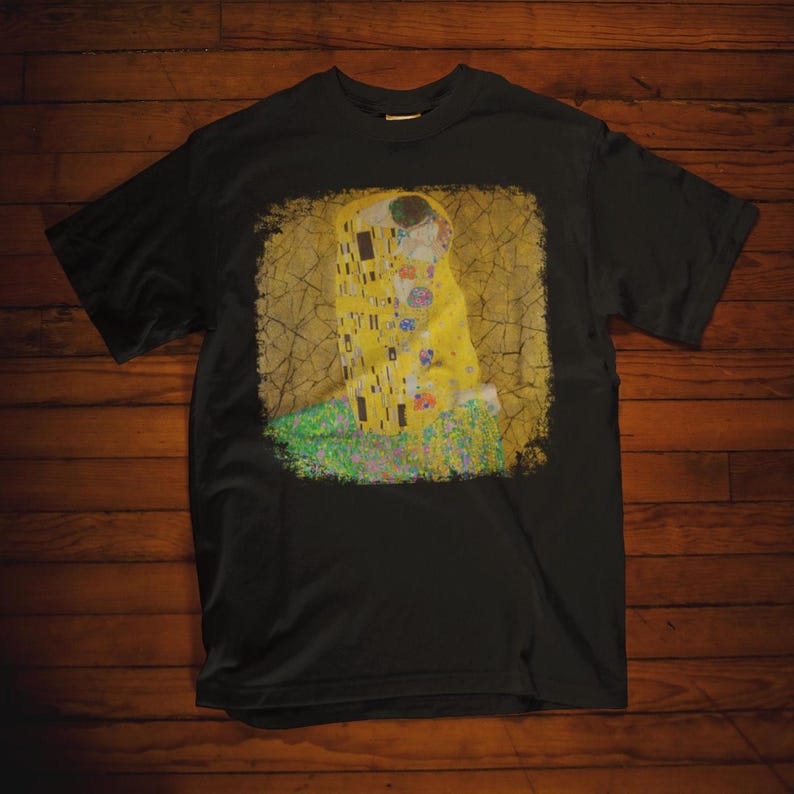 Distressed style t-shirt featuring Gustav Klimt painting The Kiss, rendered in faded gold and black tones on soft, white cotton fabric, suitable for art lovers.
