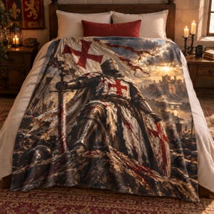 May include: A soft throw blanket featuring a detailed illustration of a medieval knight in full armour, holding a sword and shield with red cross emblems. The scene depicts a battlefield with a castle in the background under a bright sun.