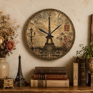 Pode incluir: Um relógio de parede redondo com uma ilustração de estilo vintage da Torre Eiffel em Paris, algarismos romanos pretos e dois ponteiros pretos. O mostrador inclui texto manuscrito, um carimbo postal e detalhes florais em tons de castanho.