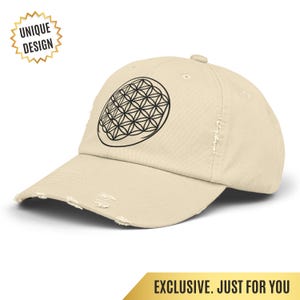 May include: A beige distressed baseball cap featuring a black and white geometric design. The cap has a curved brim and a distressed look. The words "UNIQUE DESIGN" are in a gold starburst shape.