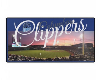 May include: A rectangular desk mat featuring a panoramic photograph of a baseball stadium at sunset with a green field, stadium lights, and spectators. The text Columbus Clippers is printed in large white script across the center of the image.