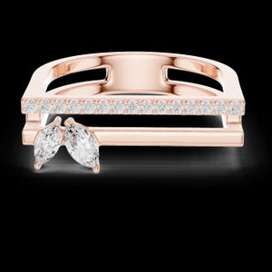 May include: Rose gold ring with a geometric design. The ring features a row of small, clear stones and two marquise-cut stones. The ring has a modern, minimalist style and is set against a black background.