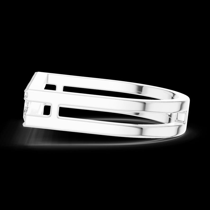 May include: A silver-colored ring with a unique, open design. The ring features a double band with rectangular cutouts and a small, square accent. The top band has a row of small, sparkling stones.