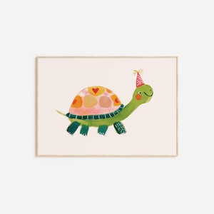 May include: A framed watercolor print of a smiling green turtle wearing a party hat. The turtle's shell is decorated with orange and pink patches and red hearts. The background is a light beige color.