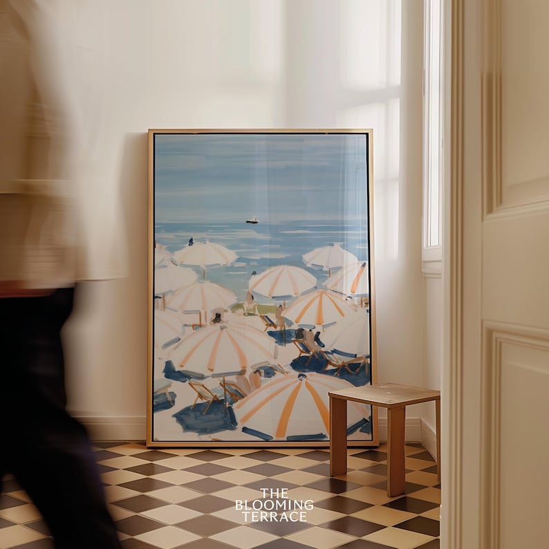 Beach scene featuring striped umbrellas and sunbathers by the calm ocean, painted in soft blue, peach, and cream tones — printable coastal wall art.