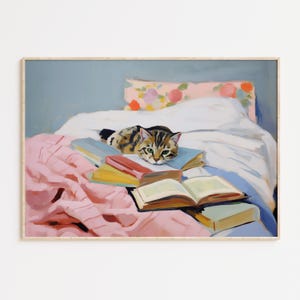 Op de afbeelding: Een tabbykat ligt op een stapel boeken op een bed met een roze deken en een wit kussen met een bloemenpatroon.