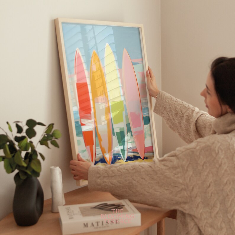 Digital wall art of four colorful surfboards in shades of coral, orange, yellow, and pink standing on a beach — perfect printable art for coastal or summer home decor.