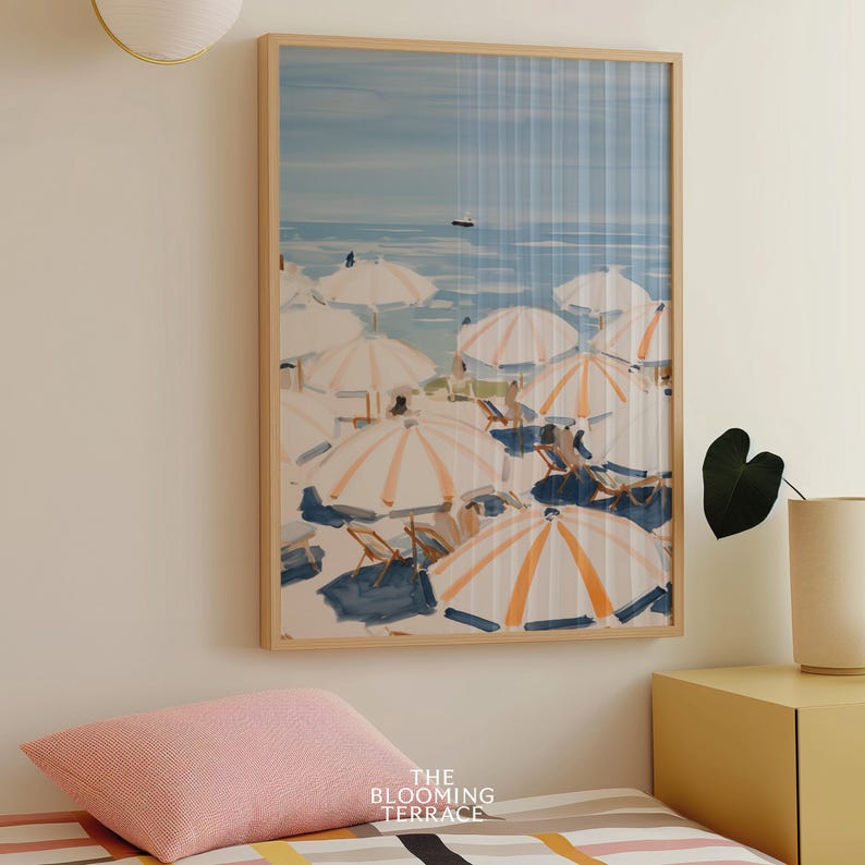 Beach scene featuring striped umbrellas and sunbathers by the calm ocean, painted in soft blue, peach, and cream tones — printable coastal wall art.