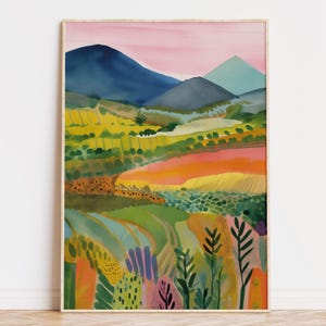 May include: A framed art print of a landscape scene, rendered in an abstract style. The artwork showcases a vibrant mix of colours, including green, yellow, orange, and blue, with a pink sky. The print is presented in a wooden frame.