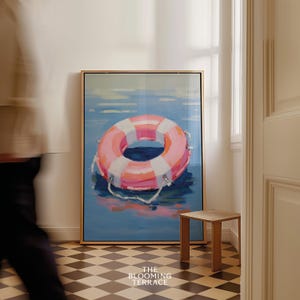 Digital painting of a pink and white lifebuoy floating on calm blue water. Bright and playful coastal art with summery, nautical vibes.