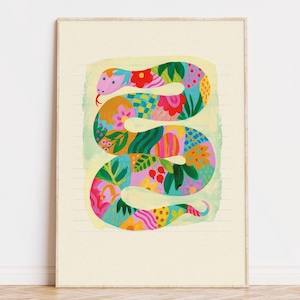 Puede incluir: Ilustración enmarcada de una serpiente con vibrantes patrones florales y geométricos. La serpiente presenta diseños en rosa, azul, amarillo y verde. El fondo es amarillo claro con finas líneas horizontales.