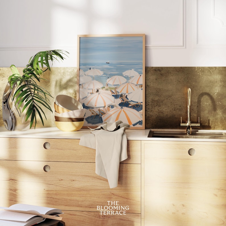 Beach scene featuring striped umbrellas and sunbathers by the calm ocean, painted in soft blue, peach, and cream tones — printable coastal wall art.