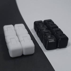 May include: Two sets of fidget toys are shown, one white and one black, against a monochrome backdrop. Each set comprises six connected, cube-shaped pieces. The cubes feature a hinged design, enabling manipulation. The toys are designed for stress relief.