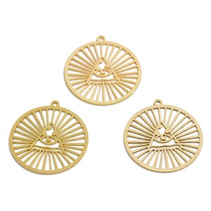 Puede incluir: Tres dijes de metal de color dorado con un diseño de ojo que todo lo ve. Cada dije es circular con un patrón de rayos de sol radiantes.