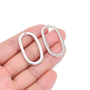 May include: Two silver-toned metal oval-shaped jewellery charms with a smooth, polished finish. Each charm features a hollow centre and a small circular hole at the top for attachment, designed for use in jewellery making or craft projects.