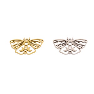 Puede incluir: Dos abalorios de mariposa de metal, uno dorado y otro plateado, con intrincados diseños recortados.