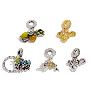 May include: Five silver charms with colorful enamel details. One charm features a bicycle with pink flowers, another says "Hello Summer", and others depict a pineapple, a flower, and a bicycle with a basket. These charms are designed for bracelets.