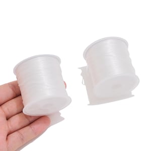 May include: Two spools of clear, elastic cord for jewelry making. Each spool is made of white plastic and is tightly wound with a continuous length of thin, transparent, stretchy string, providing a clear view of the material texture.