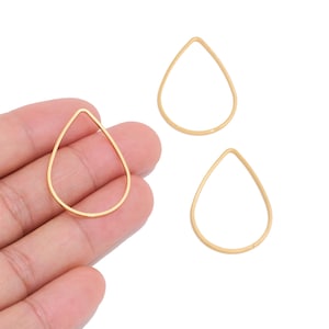 May include: Three gold-colored metal teardrop-shaped open frames. Each frame consists of a thin, smooth wire bent into a symmetrical droplet outline. The frames are uniform in size and shape, featuring a polished metallic finish throughout.