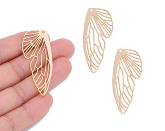 May include: Three gold-coloured metal charms shaped like insect wings. Each charm features a delicate, openwork filigree pattern mimicking the veins of a wing and includes a small circular hole at the top for attachment or hanging purposes.