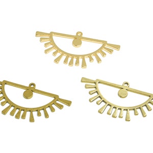 Puede incluir: Tres abalorios de metal dorado en forma de ojo con un diseño de sol. Cada abalorio tiene un pequeño círculo en el centro del ojo.